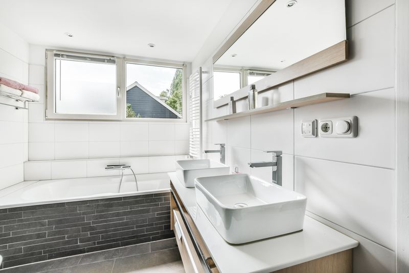 Baño luminoso con bañera revestida, lavabo sobre encimera y paredes blancas